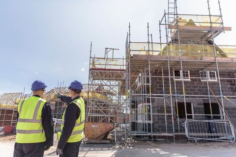 Builders discussing housing development on building site