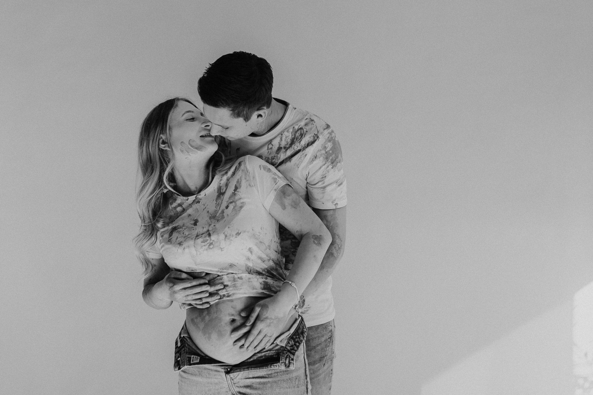 Auf einem Schwarzweißfoto küssen sich ein Mann und eine schwangere Frau.
