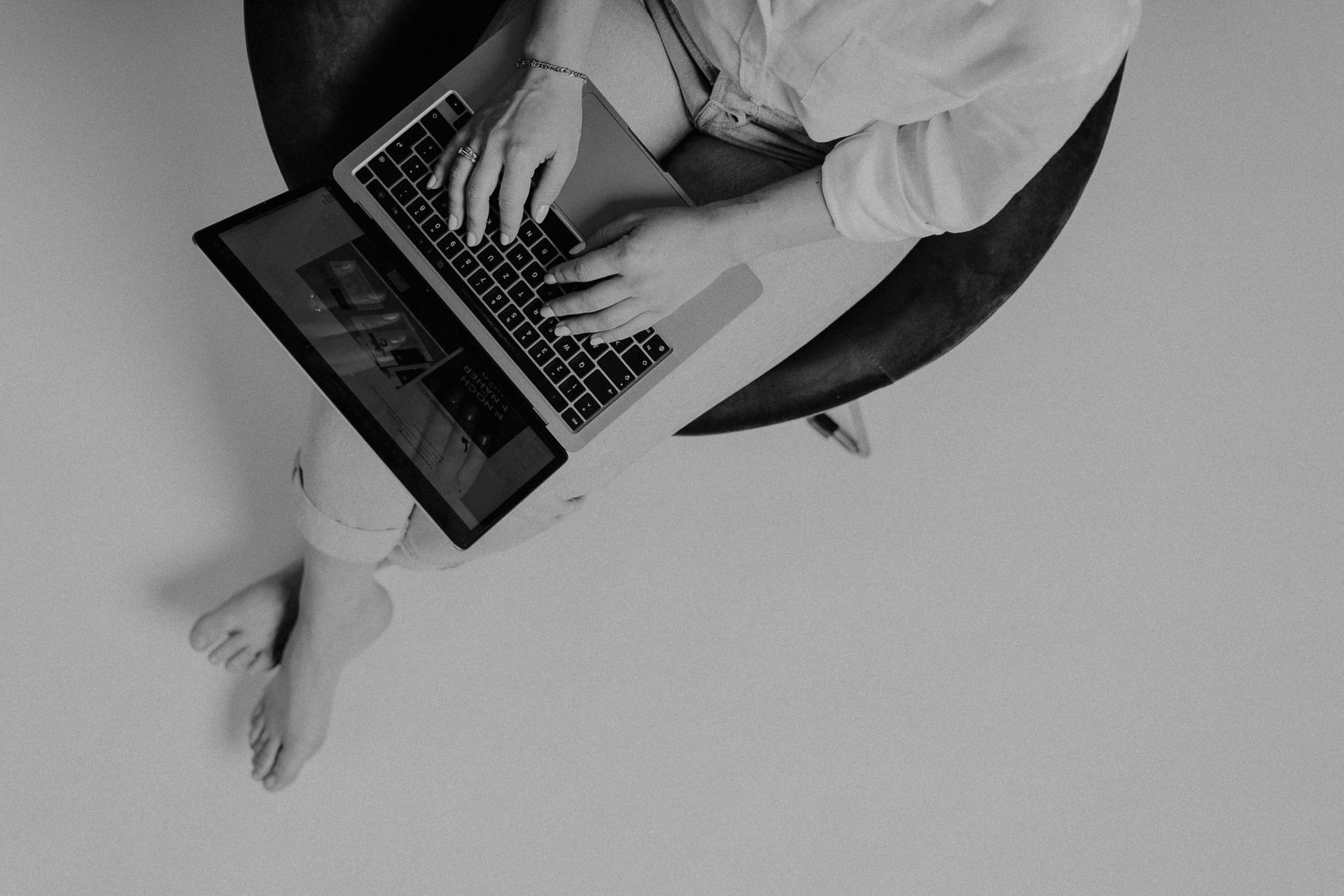 Eine Frau sitzt auf einem Stuhl und benutzt einen Laptop.