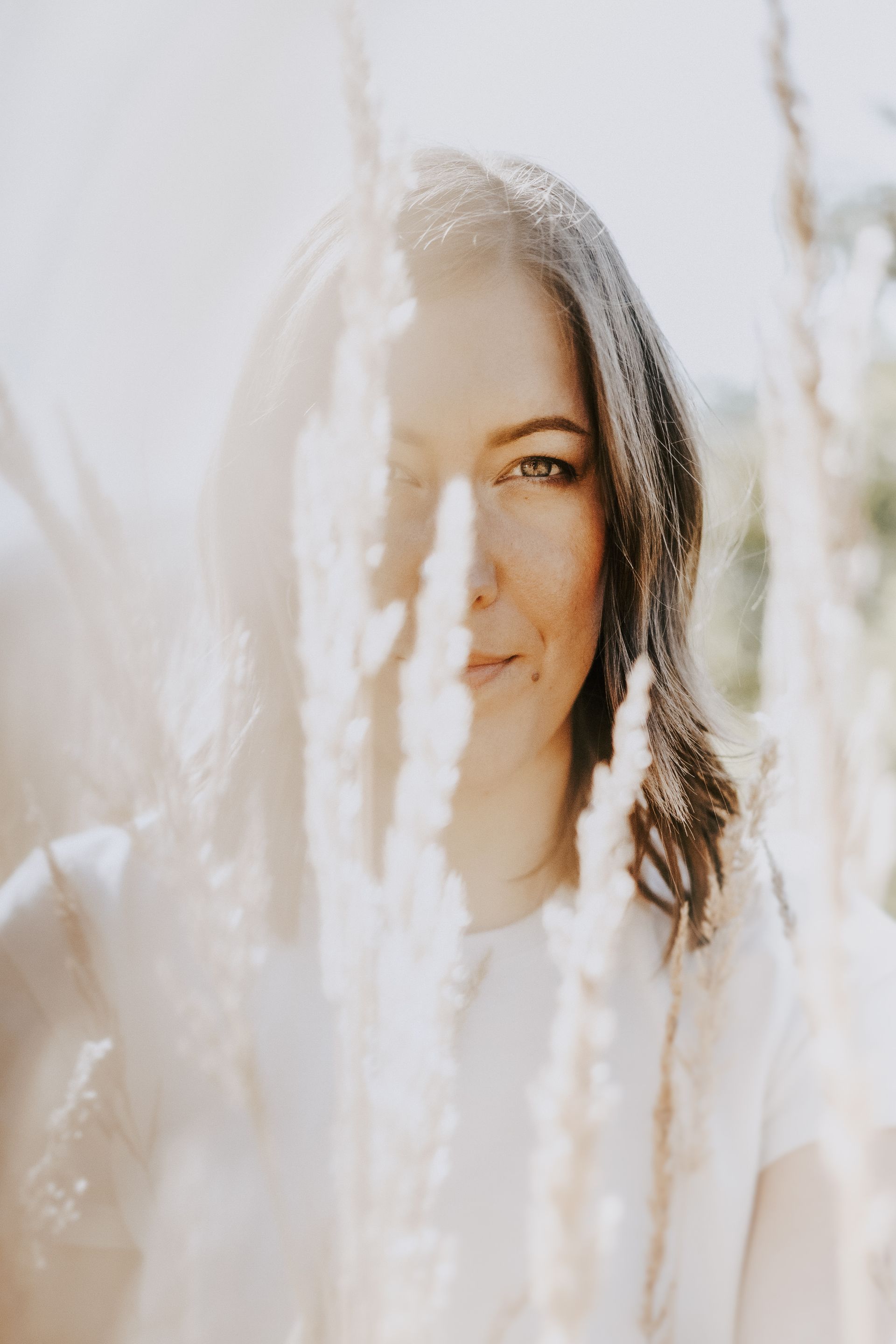 Eine Frau steht vor einem Feld mit hohem Gras.