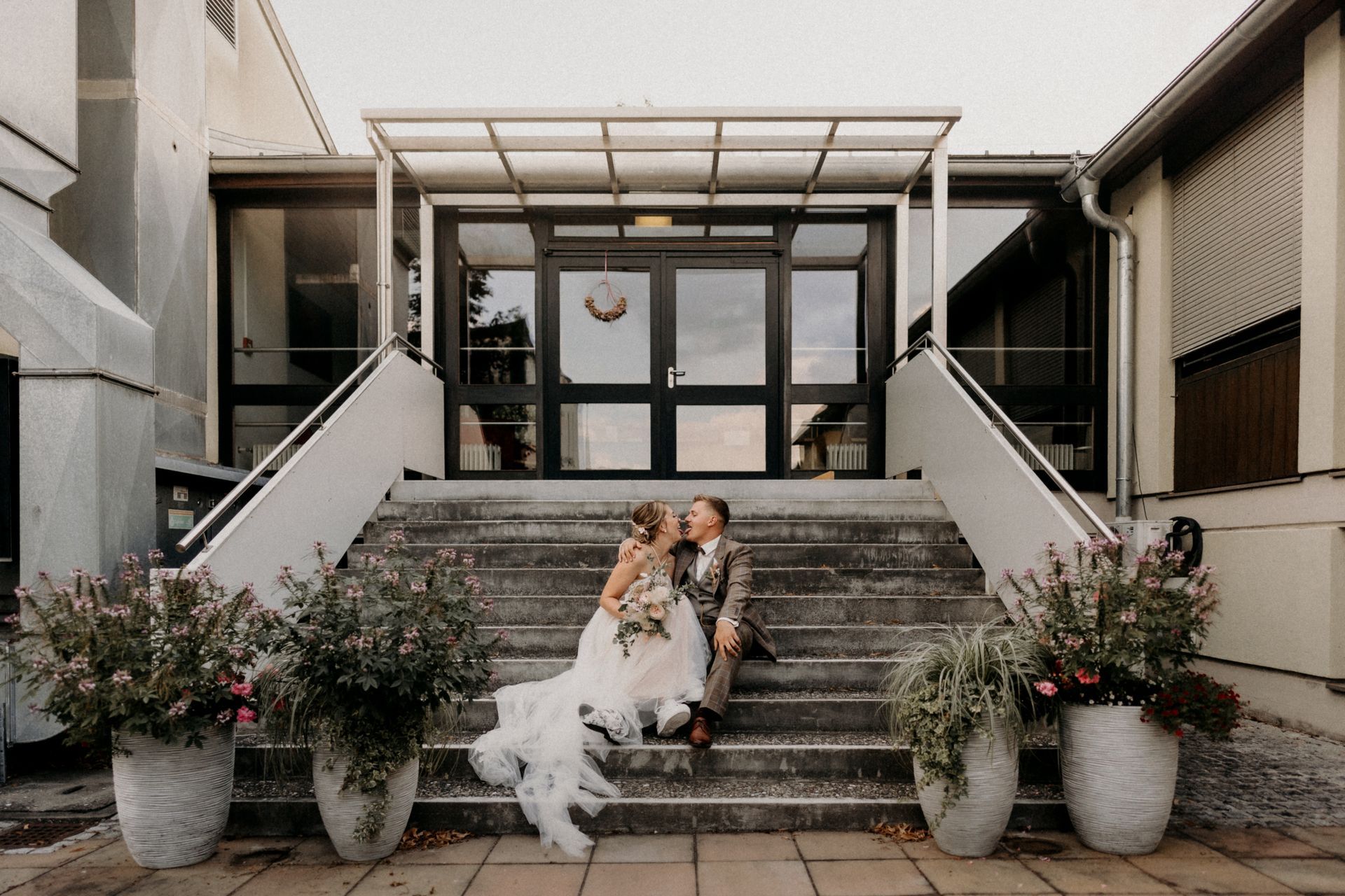 Eine Braut und ein Bräutigam sitzen auf den Stufen eines Gebäudes.