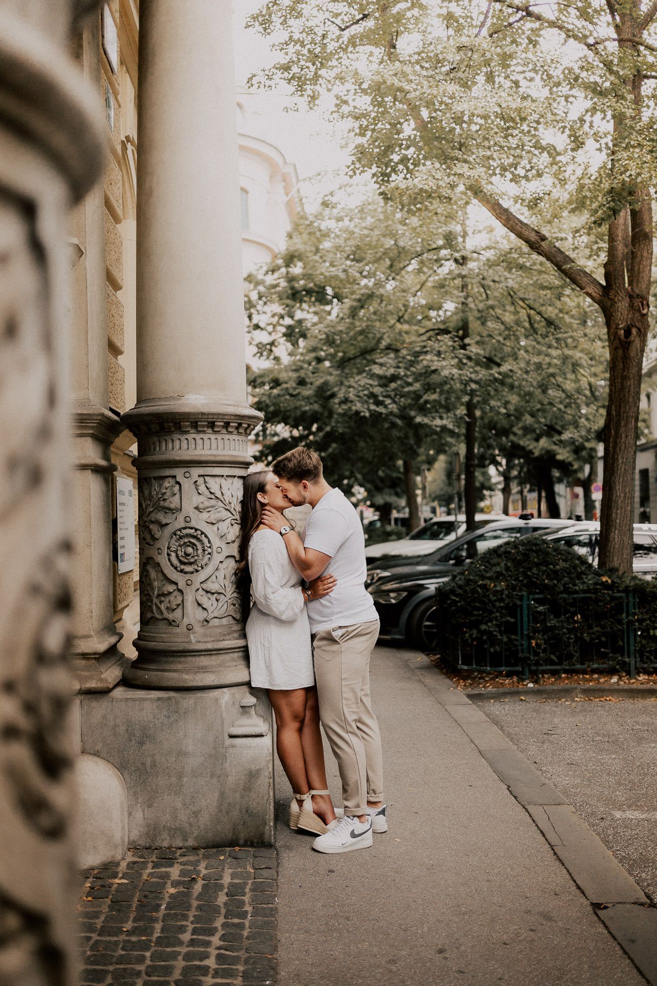 Paar lehnt an einer Wand und küsst sich zärtlich