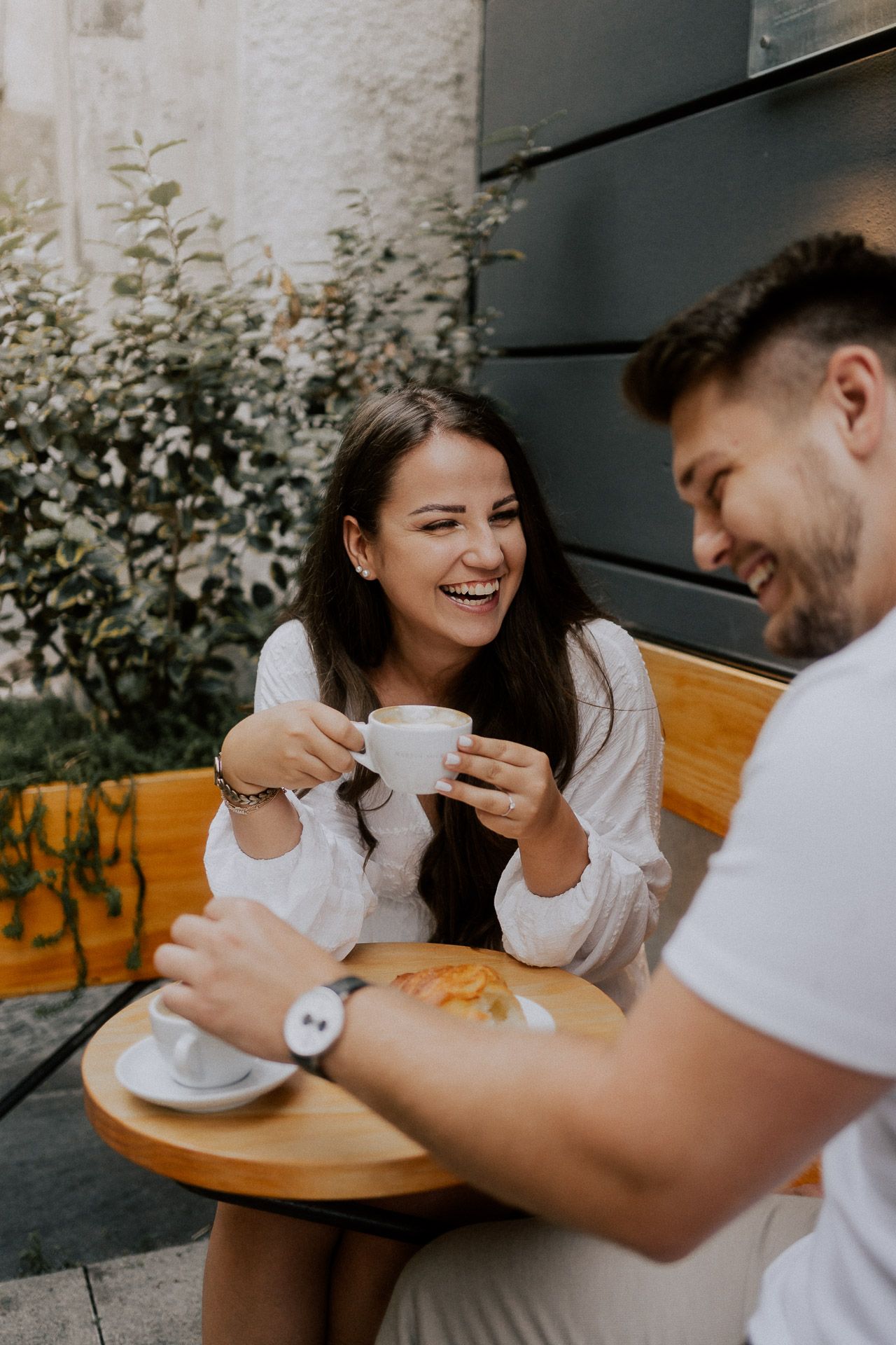 Paarfotos in einem Café, Sie lacht ihn herzlich mit Kaffee in der Hand an