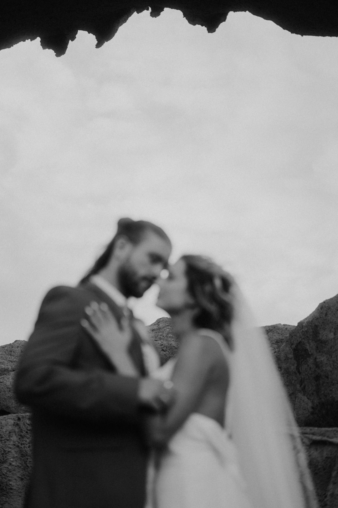Auf einem Schwarzweißfoto küssen sich Braut und Bräutigam.
