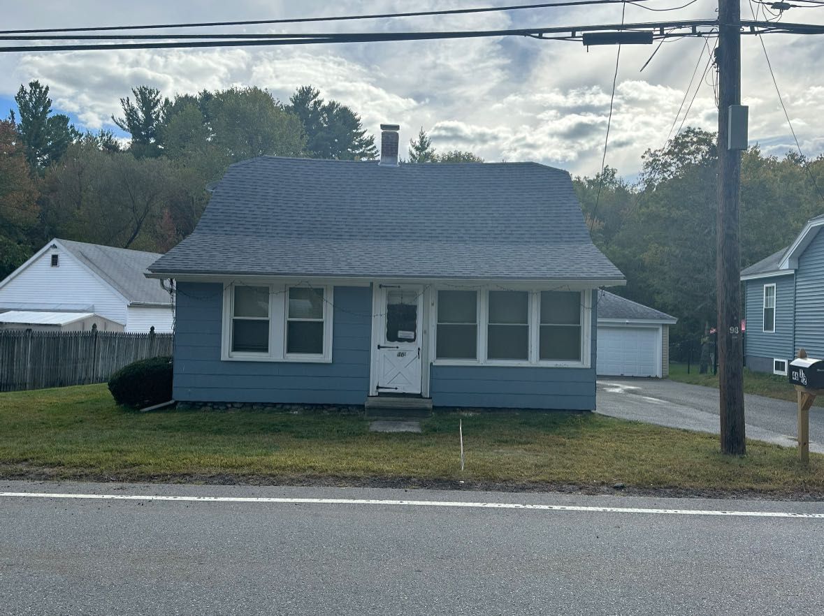 Blue house with multiple windows, small yard, and a gray roof.