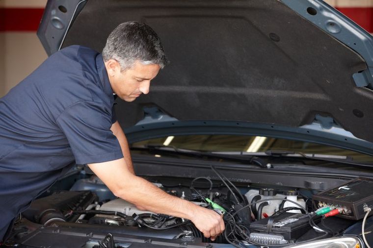 a man is working on the engine of a car with the hood open .