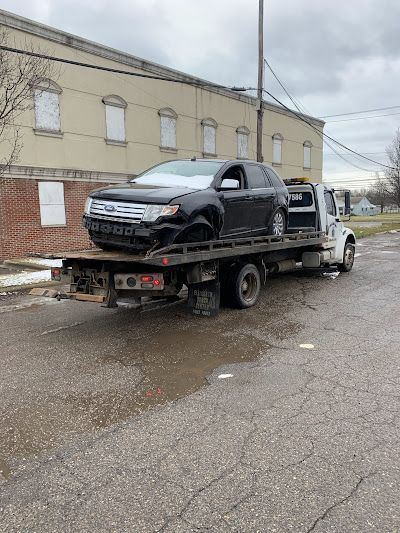 A black car is being towed by a tow truck.