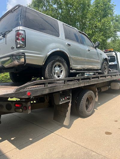 A silver suv is sitting on top of a tow truck.