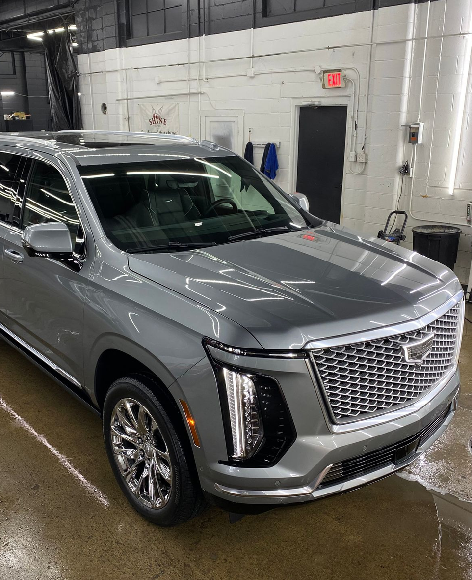Silver SUV in a car wash bay with wet floor and white tiled walls