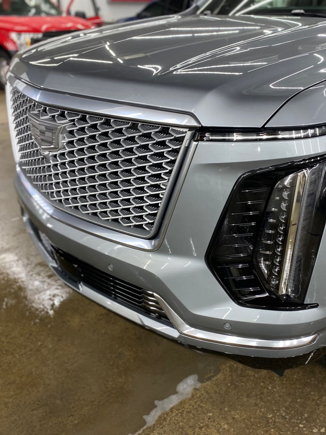 Front view of a silver SUV with chrome grille and LED headlights in a wet indoor garage