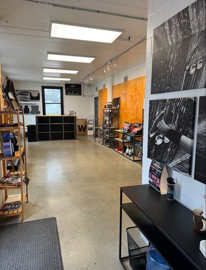 Bright retail shop interior with shelves, black counters, orange wall, and overhead fluorescent lights