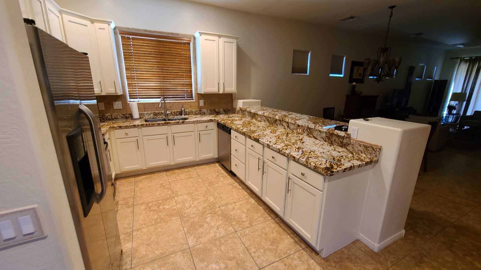 Kitchen with white cabinets, granite countertops, and tile flooring.