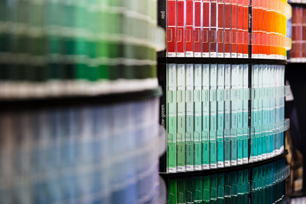 Paint color swatches displayed in a circular rack, showcasing various shades of green, red, and blue.