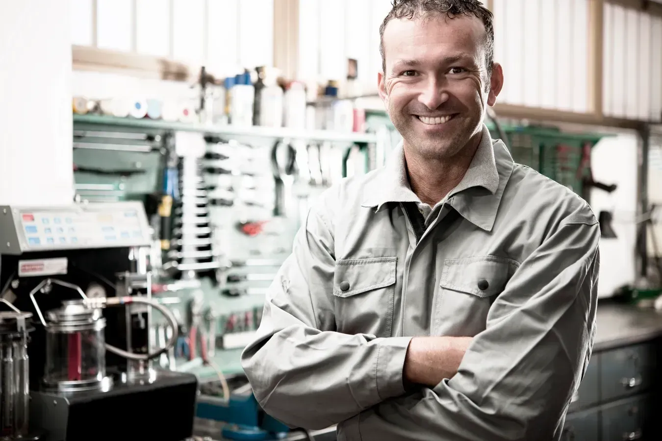 A man is standing in a garage with his arms crossed and smiling.  | Royal Expert Auto Service & Discount Tire Center