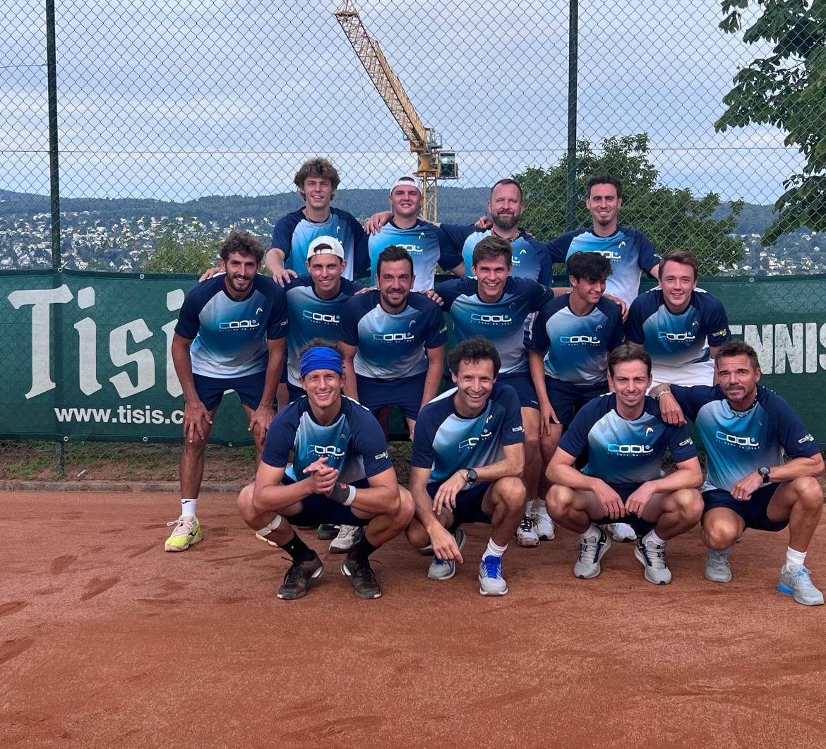 Eine Tennismannschaft posiert für ein Foto vor einem Schild mit der Aufschrift „Tisi“.