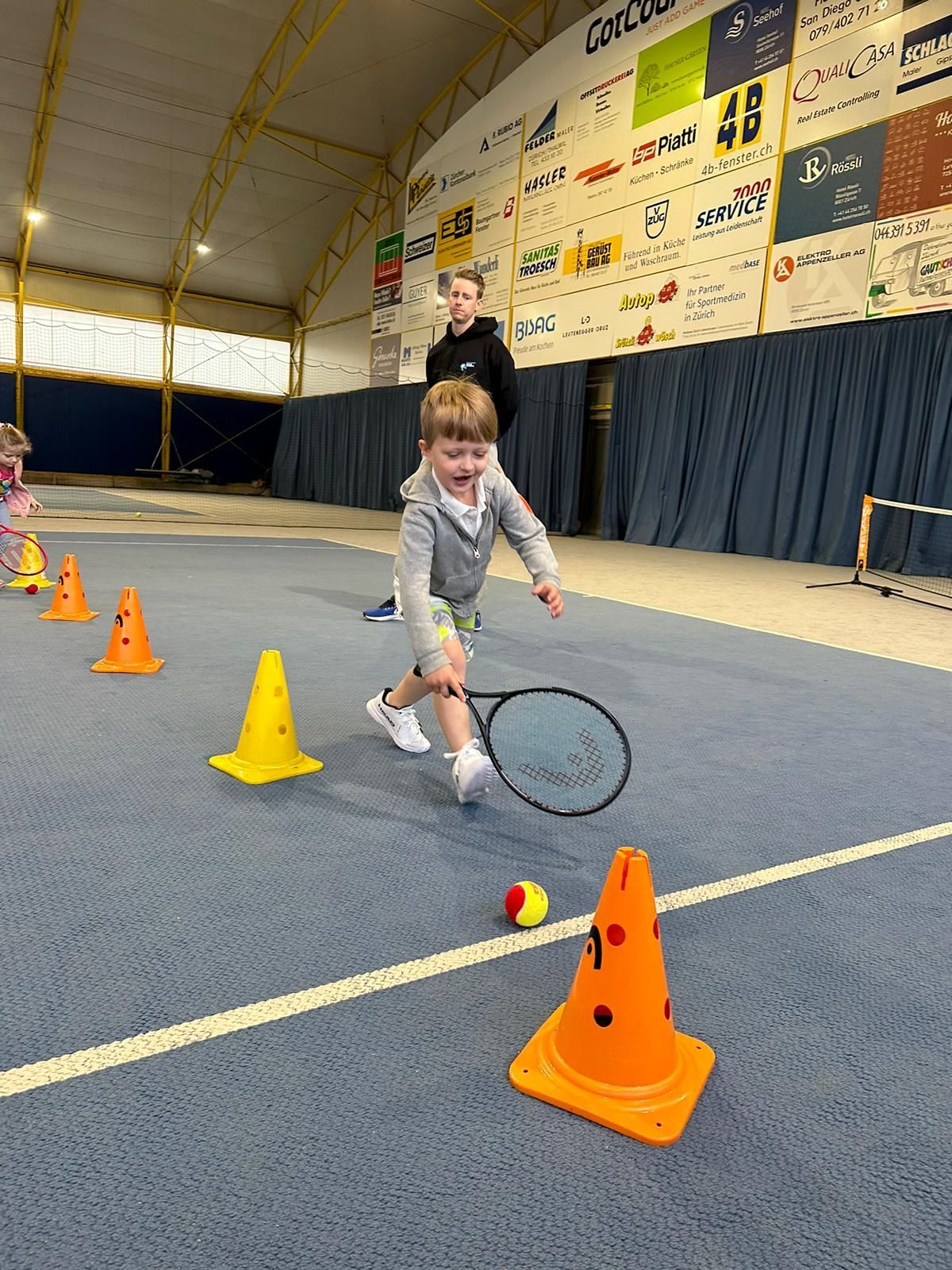 Ein kleiner Junge spielt Tennis auf einem Tennisplatz.