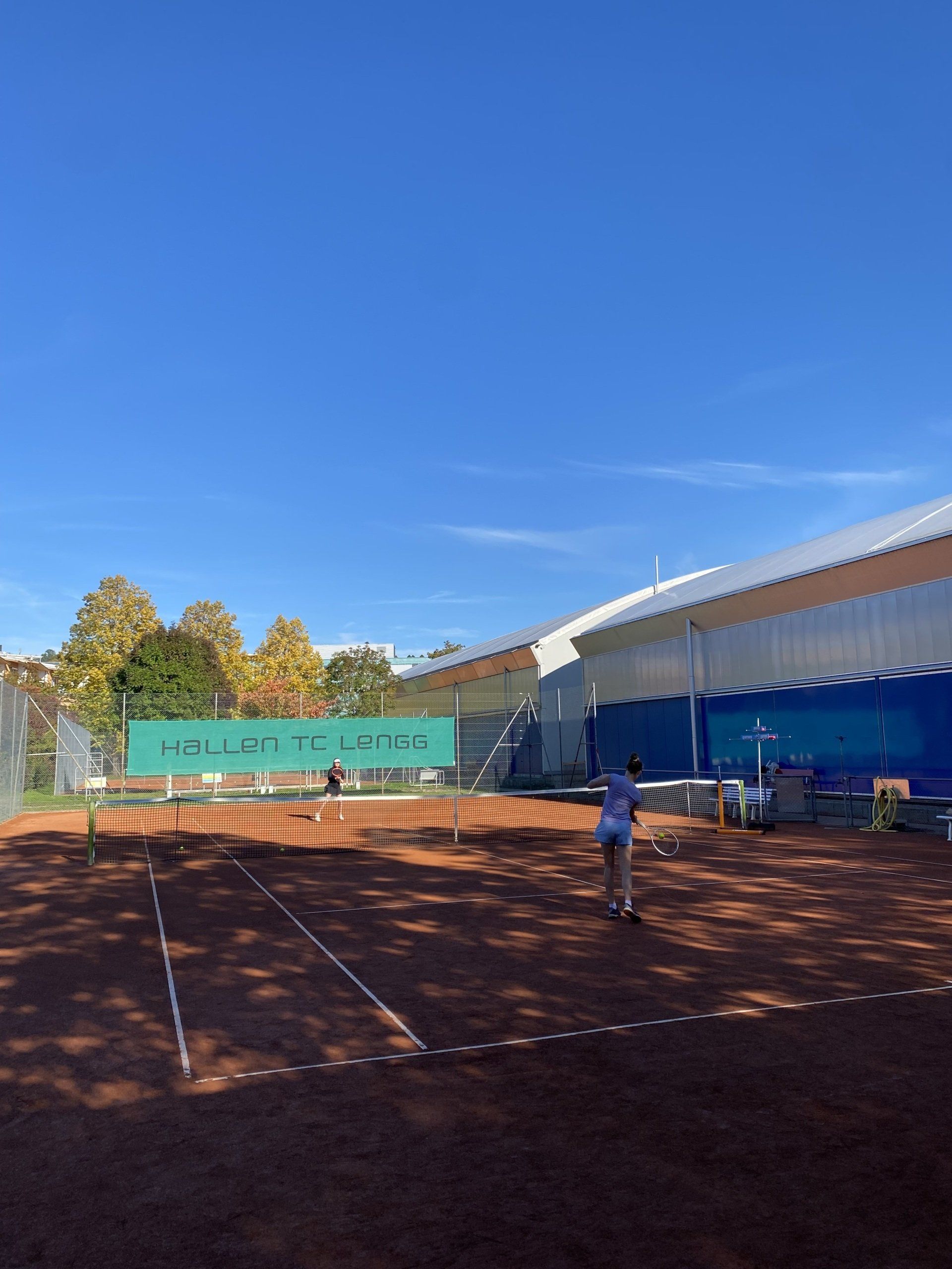 Eine Person spielt Tennis auf einem Tennisplatz.