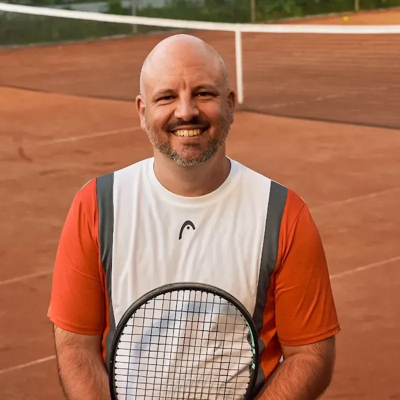 Ein Mann hält einen Tennisschläger mit einem Head-Logo darauf