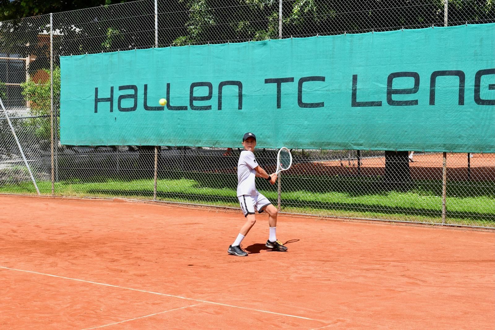 Ein Mann spielt Tennis auf einem Platz vor einem Banner mit der Aufschrift „Halle TC Leng“
