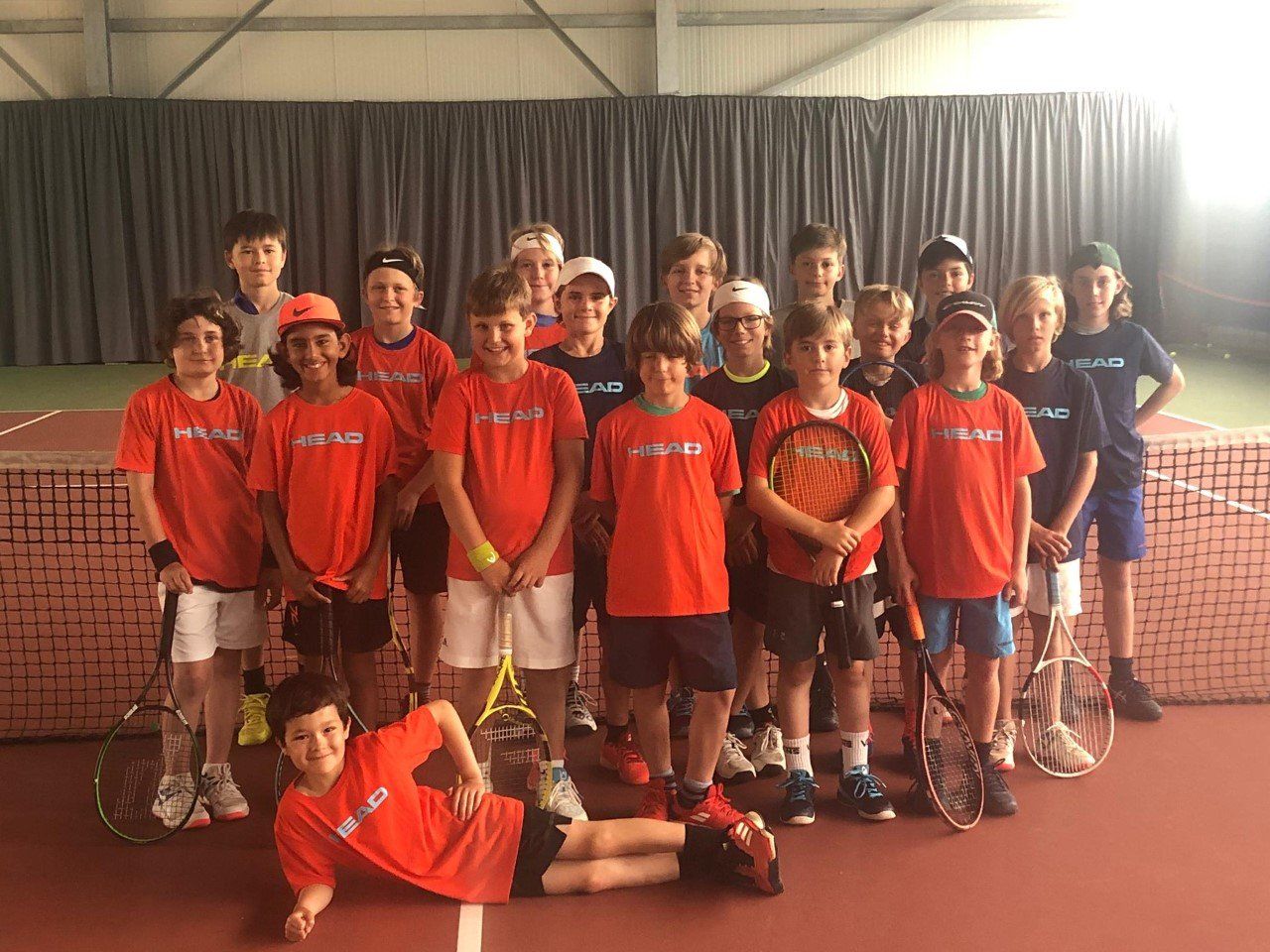 Eine Gruppe junger Jungen posiert auf einem Tennisplatz für ein Foto.