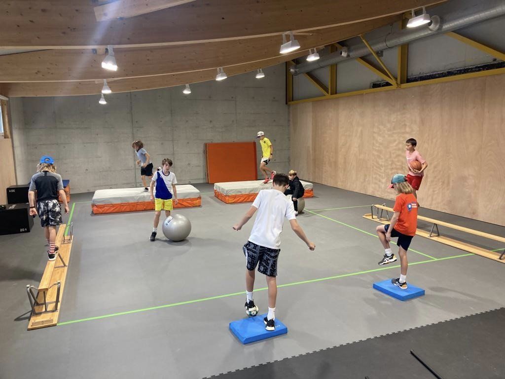 Eine Gruppe Kinder macht in einer Turnhalle Übungen.