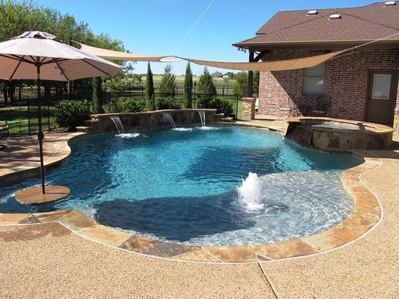 Backyard swimming pool with three wall water features, a bubbler fountain, stone coping, and a patio with a tan umbrella.