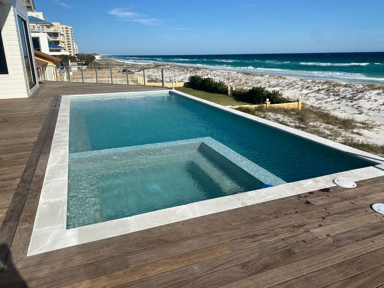Swimming pool with jacuzzi overlooking beach and ocean.