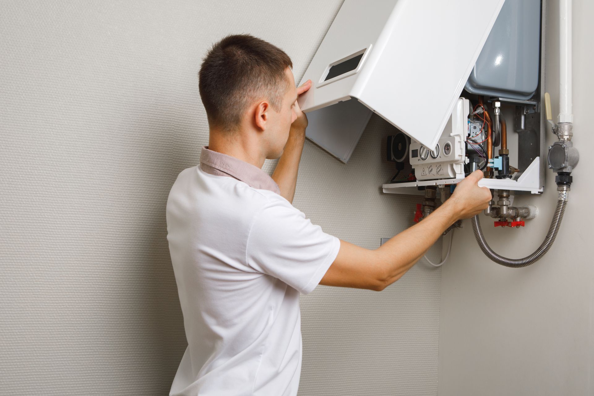 Man installs the cover on a white wall-mounted boiler.
