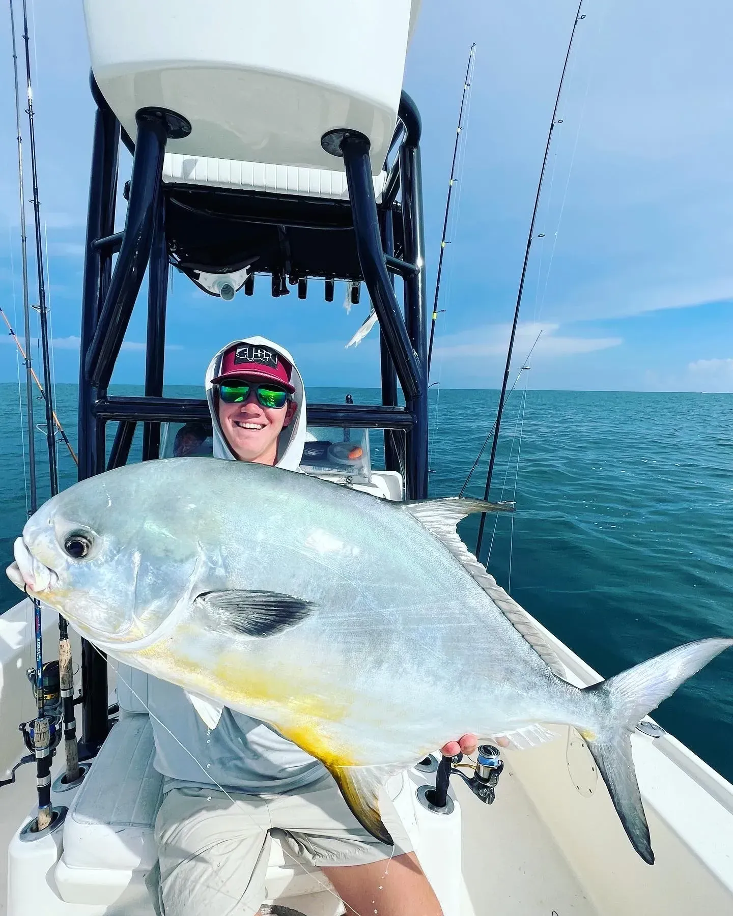 A man is sitting on a boat holding a large fish.