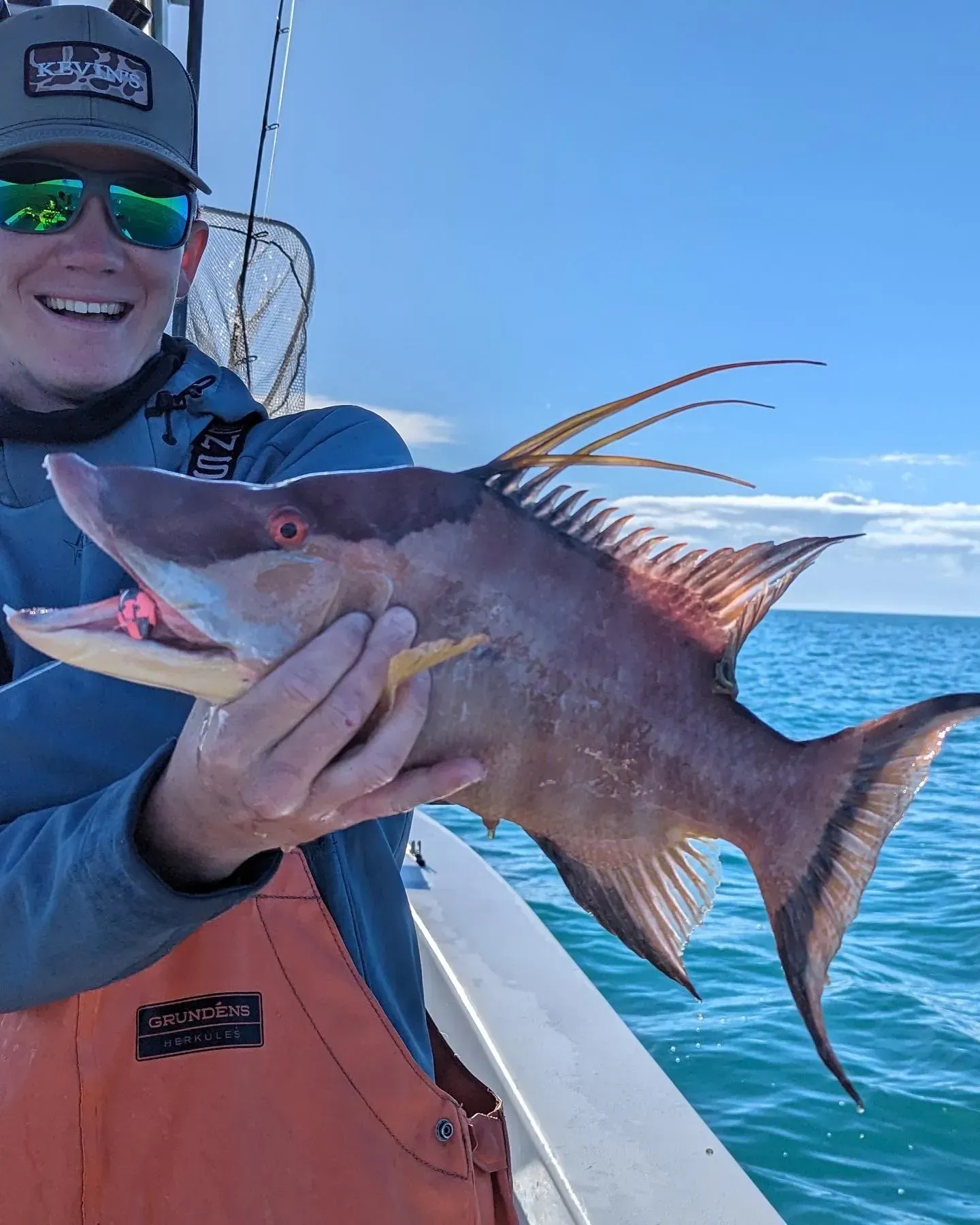 A man is holding a large fish in his hands on a boat.