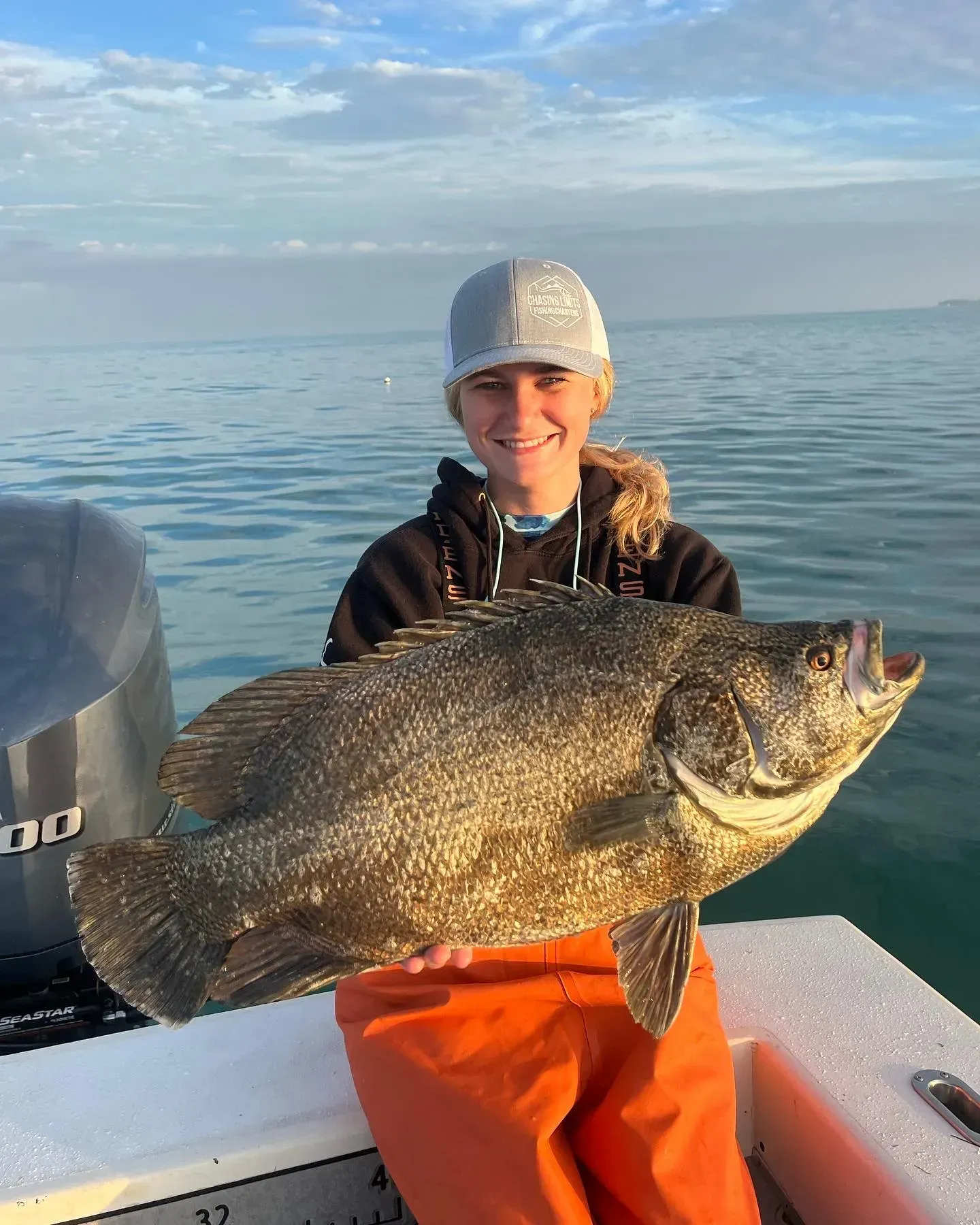A woman is holding a large fish on a boat.