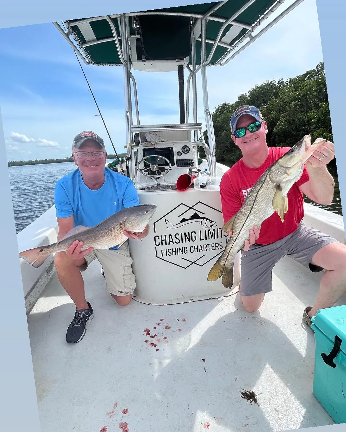 Two men are sitting on a boat holding fish.