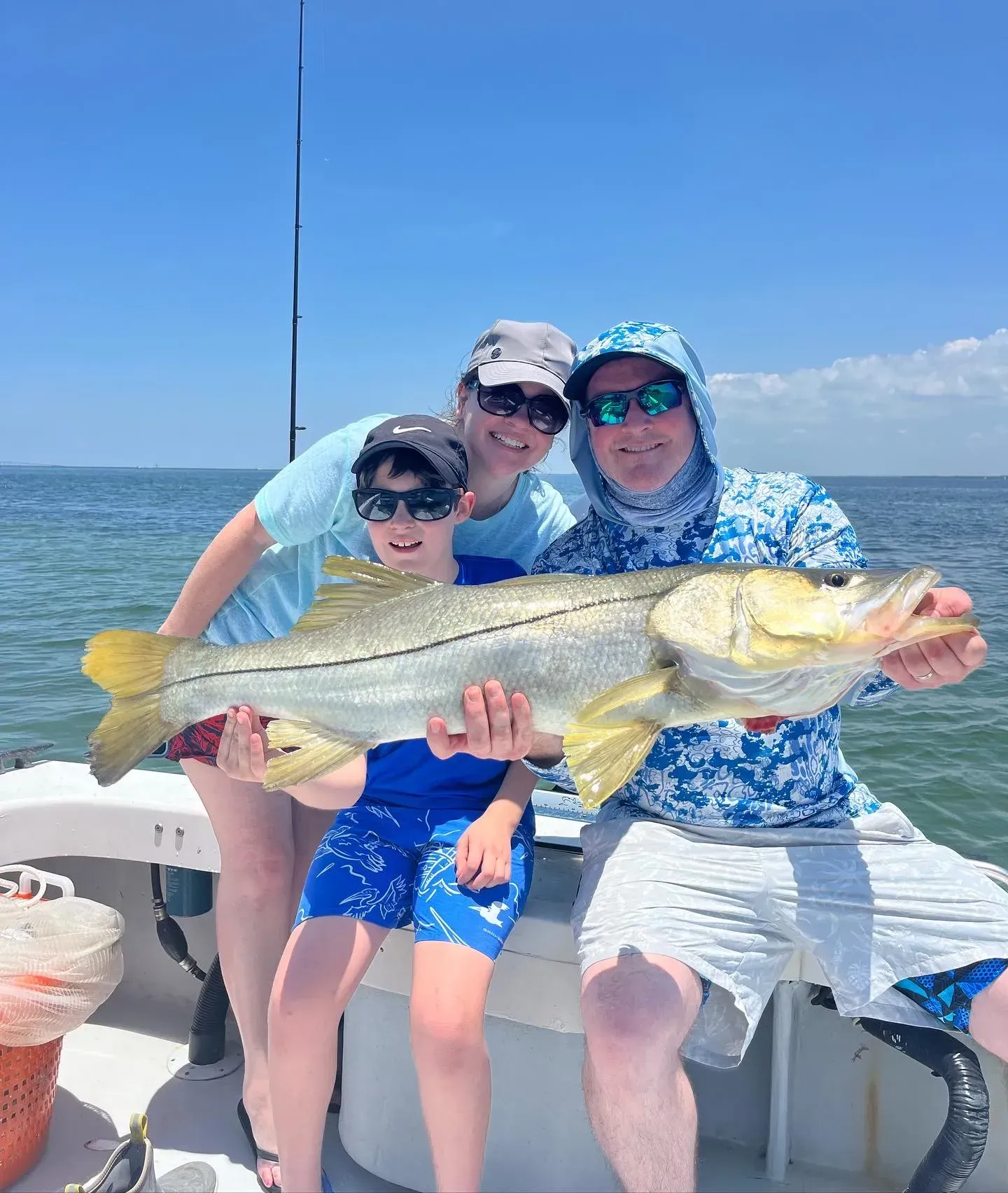 A family is sitting on a boat holding a large fish.