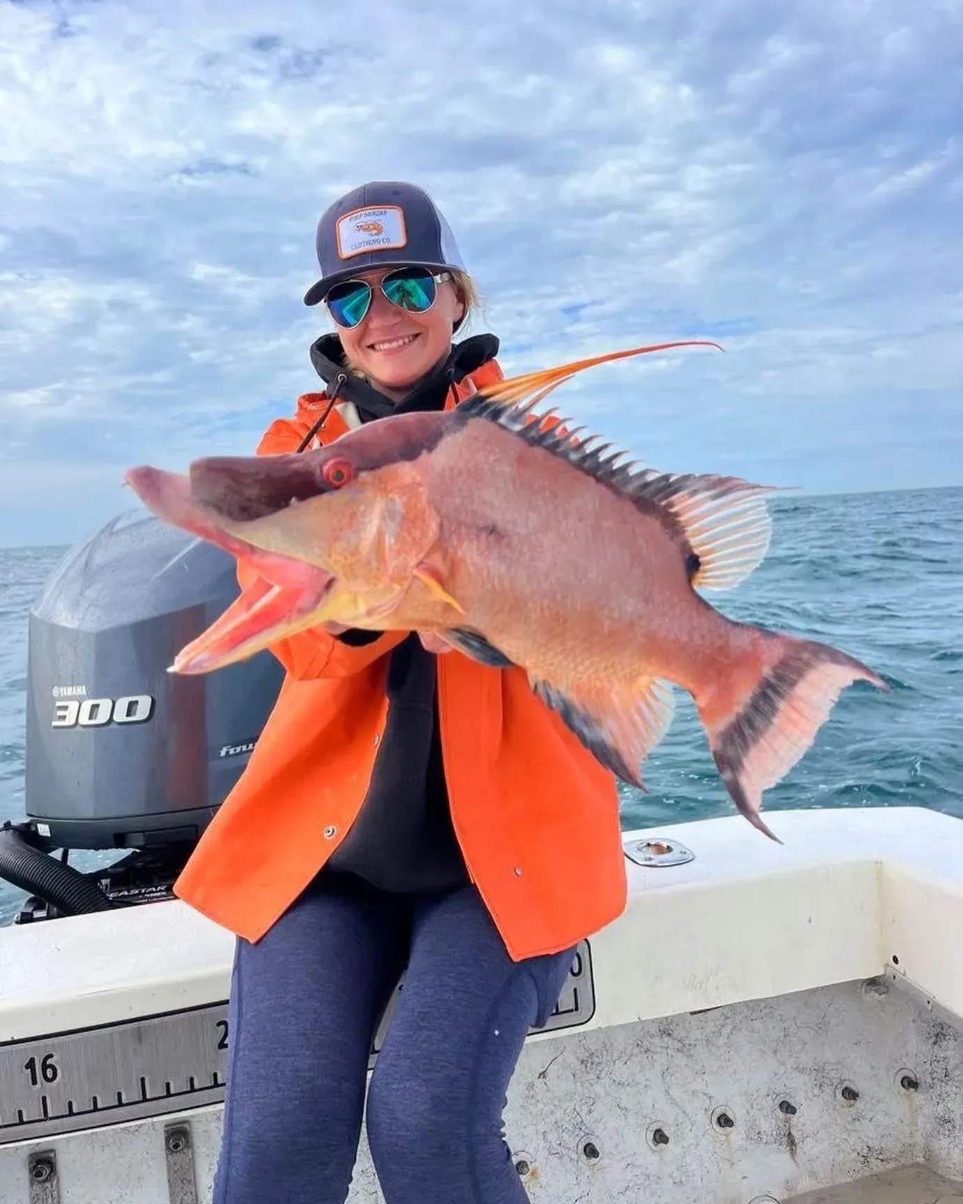 A woman is holding a large fish on a boat.