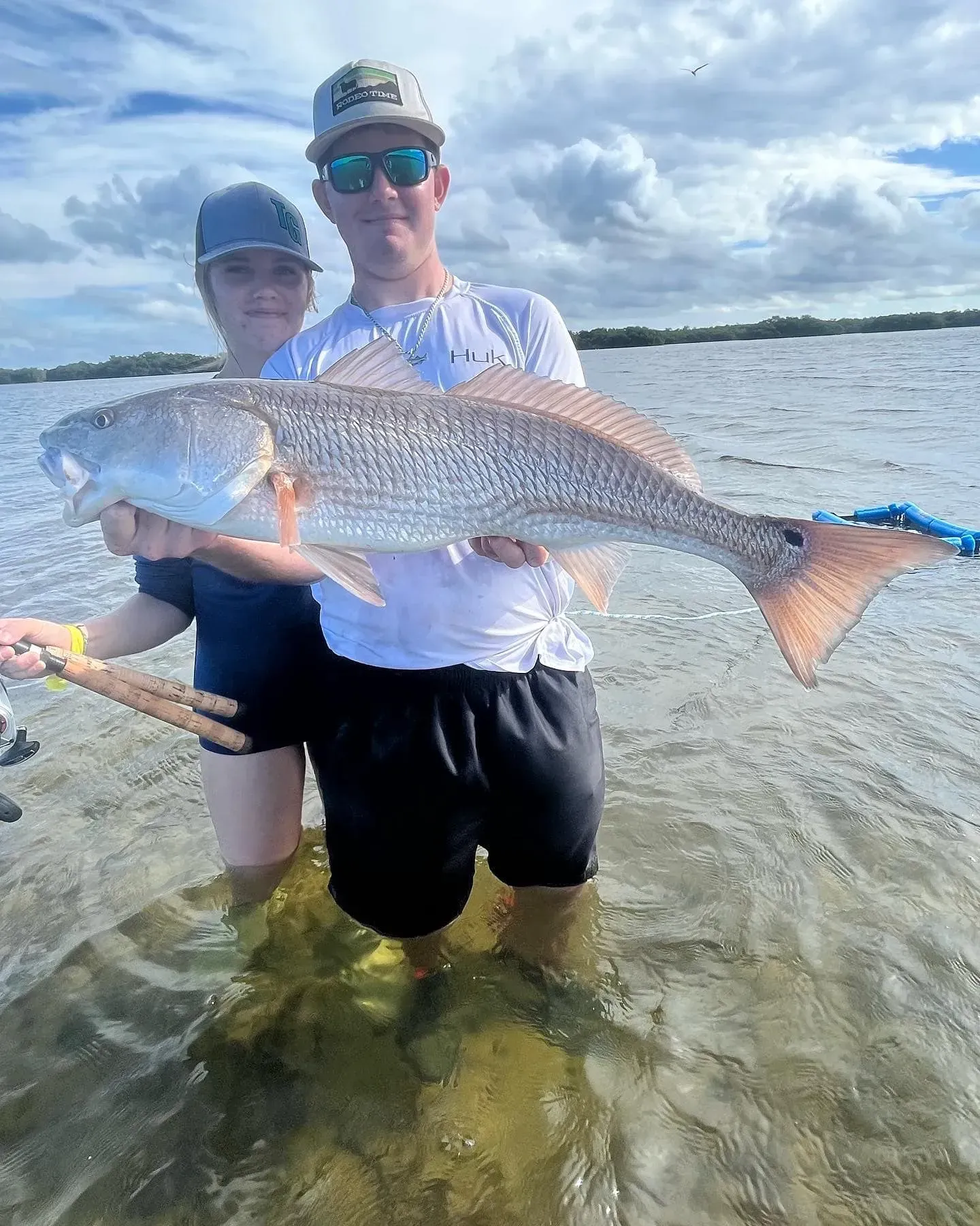 A man and a woman are holding a large fish in the water.