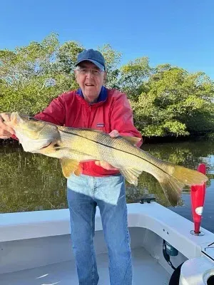 A man is holding a large fish on a boat.