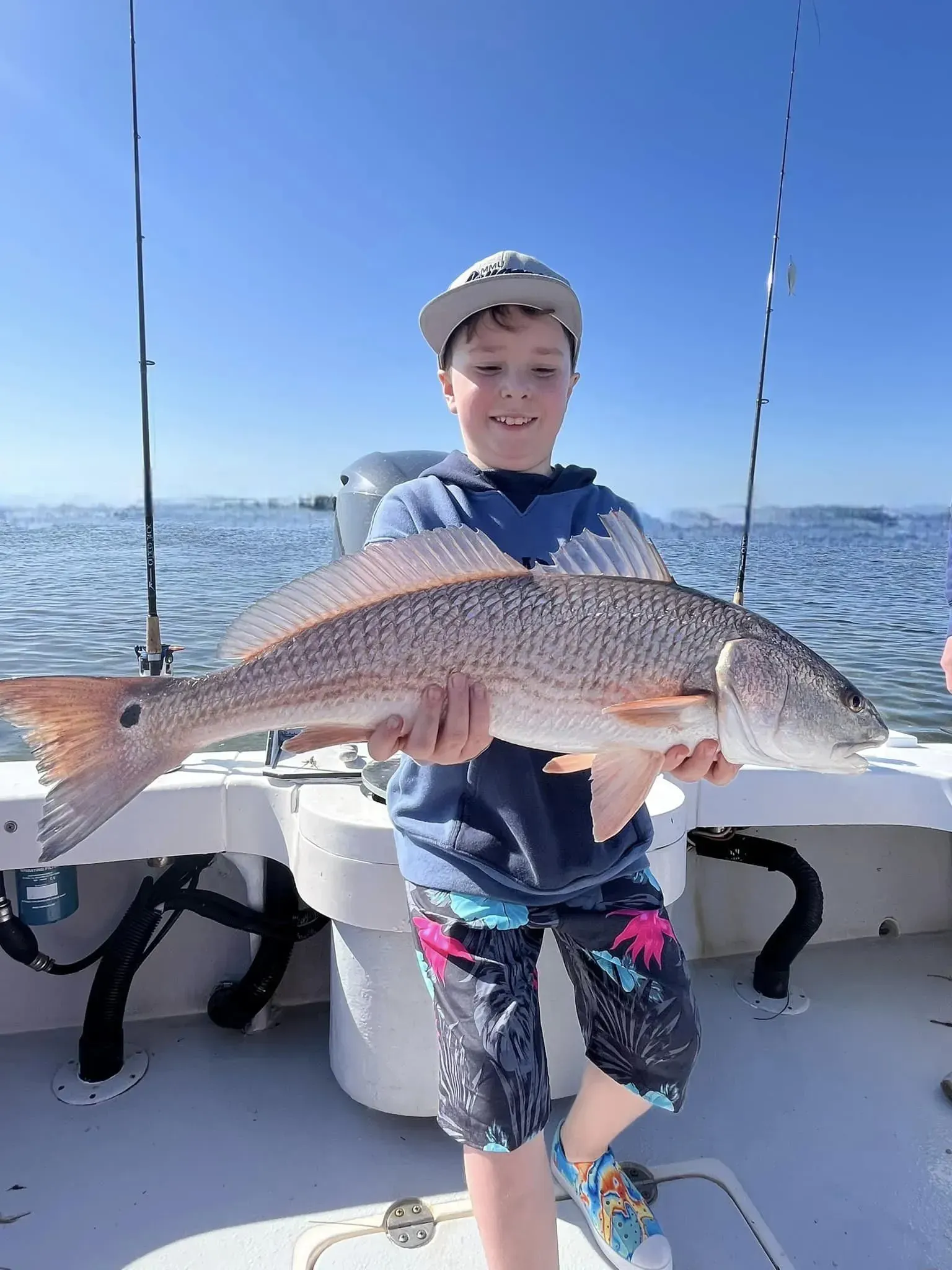 A young boy is holding a large fish on a boat.