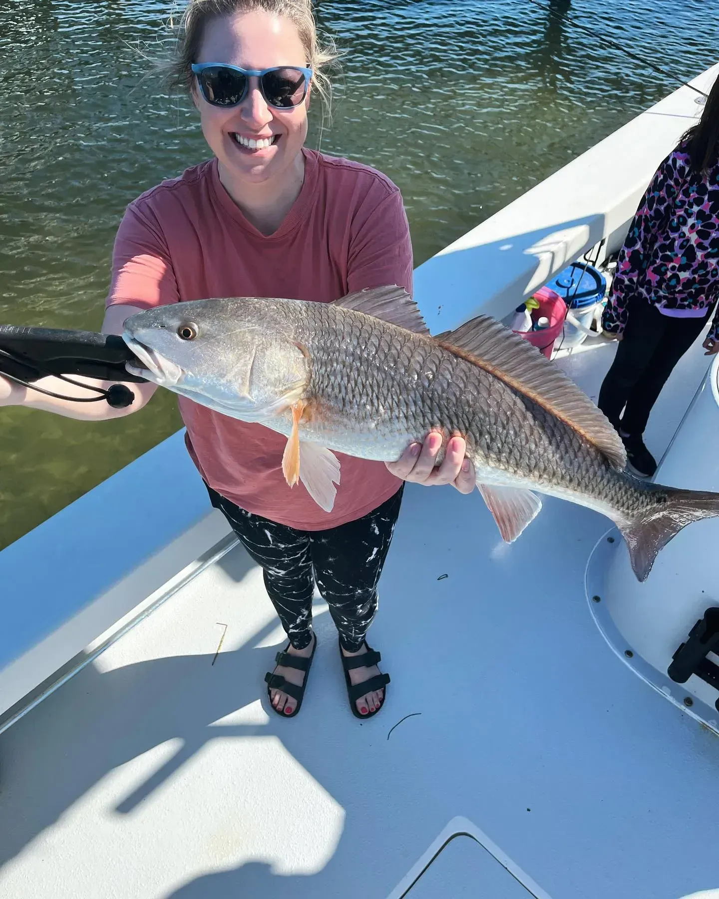 A woman is holding a large fish on a boat.