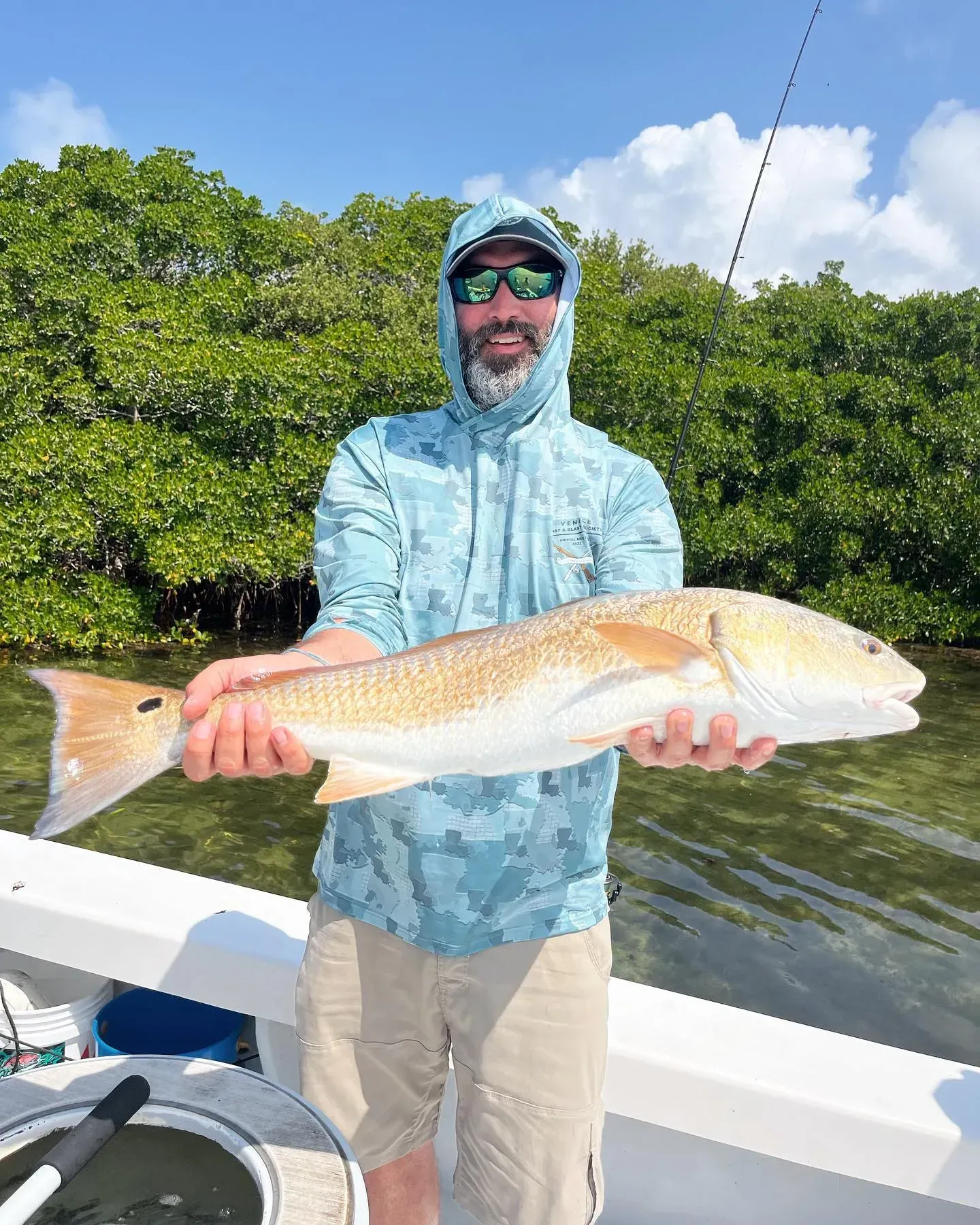 A man is holding a large fish on a boat.
