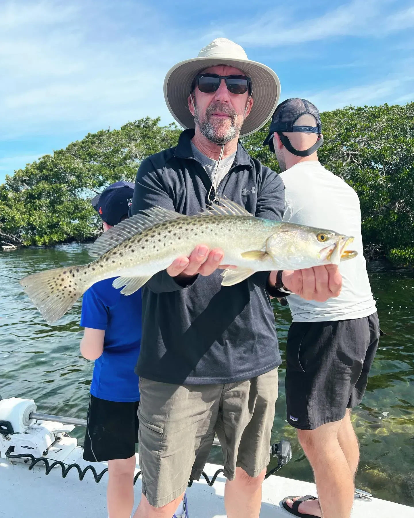 A man is holding a fish in his hands on a boat.