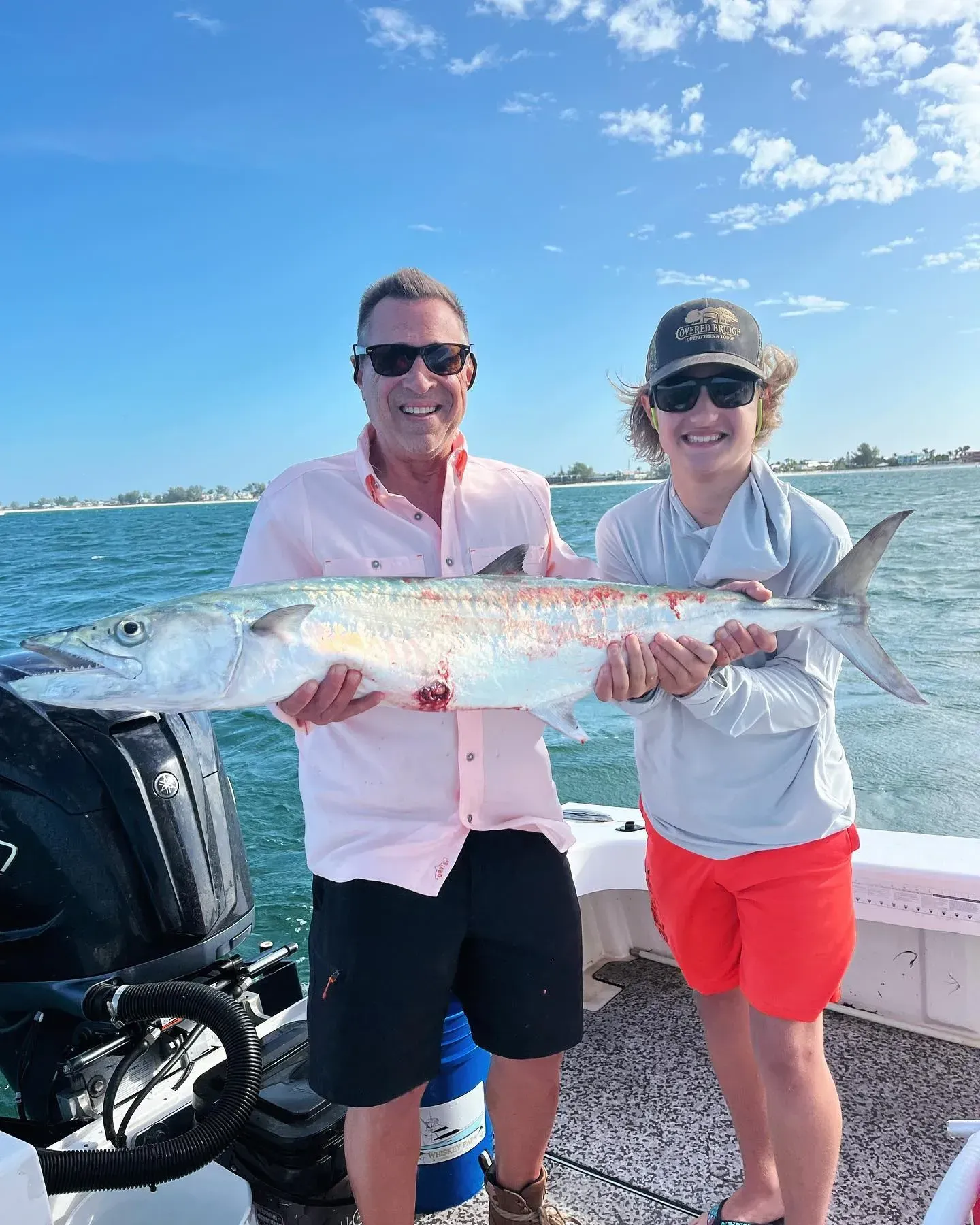 A man and a woman are holding a large fish on a boat.