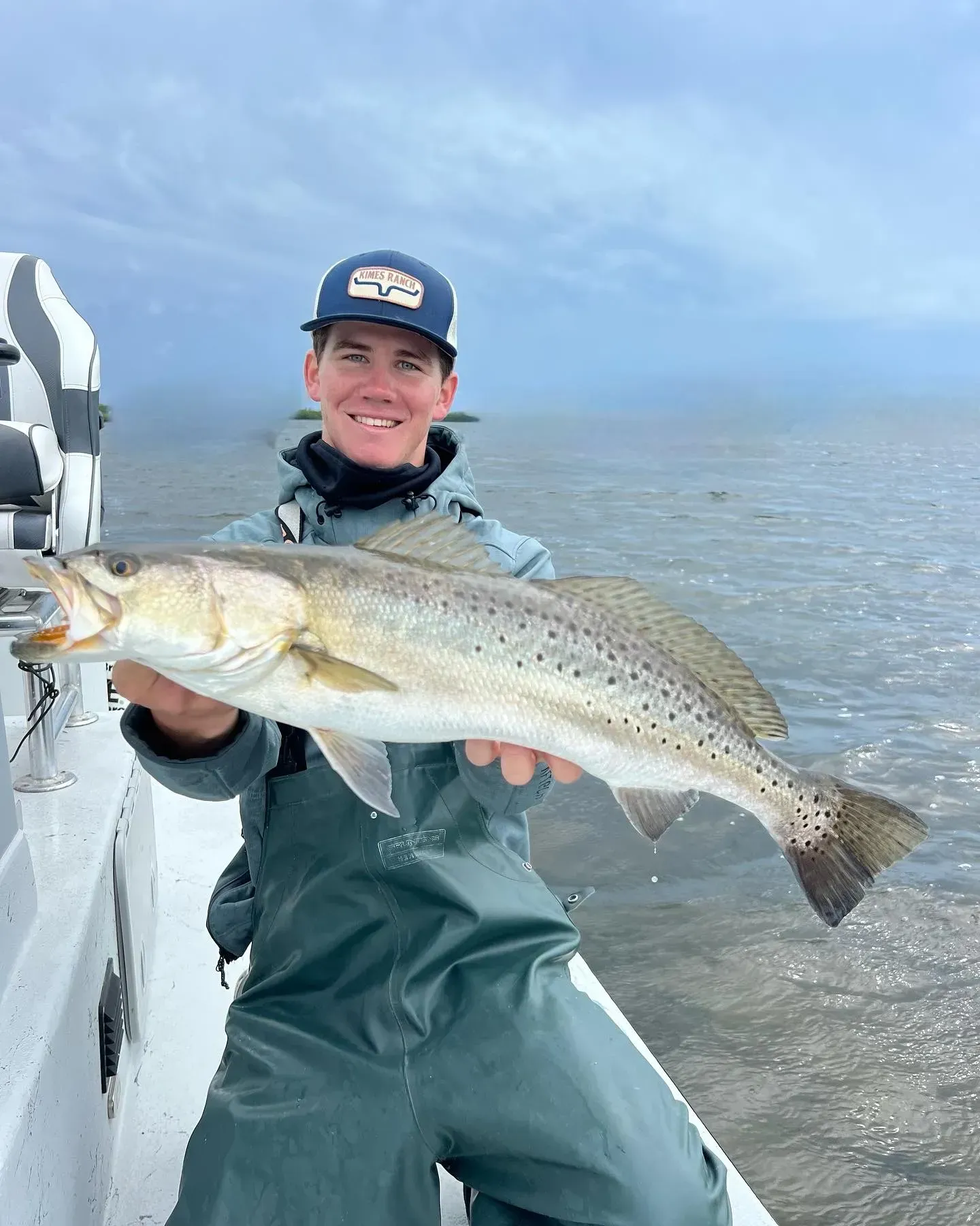 A man is holding a large fish on a boat.