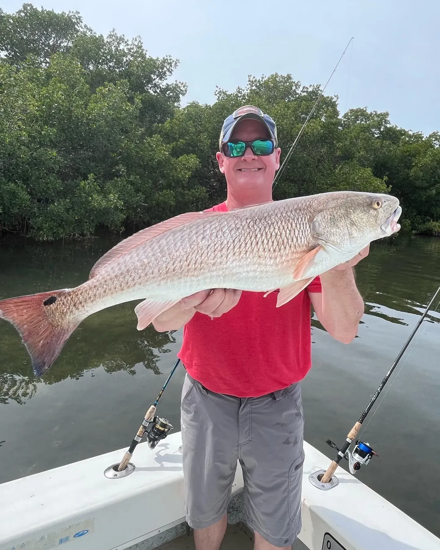 A man is standing on a boat holding a large fish.