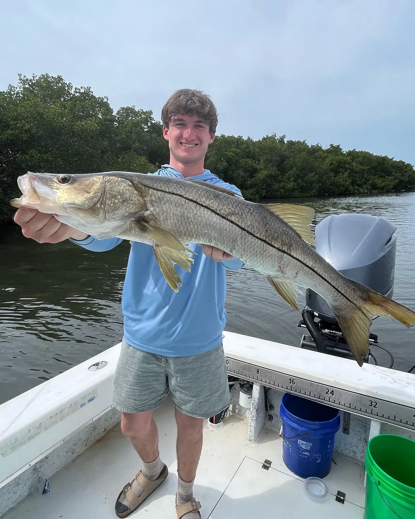 A young man is holding a large fish on a boat