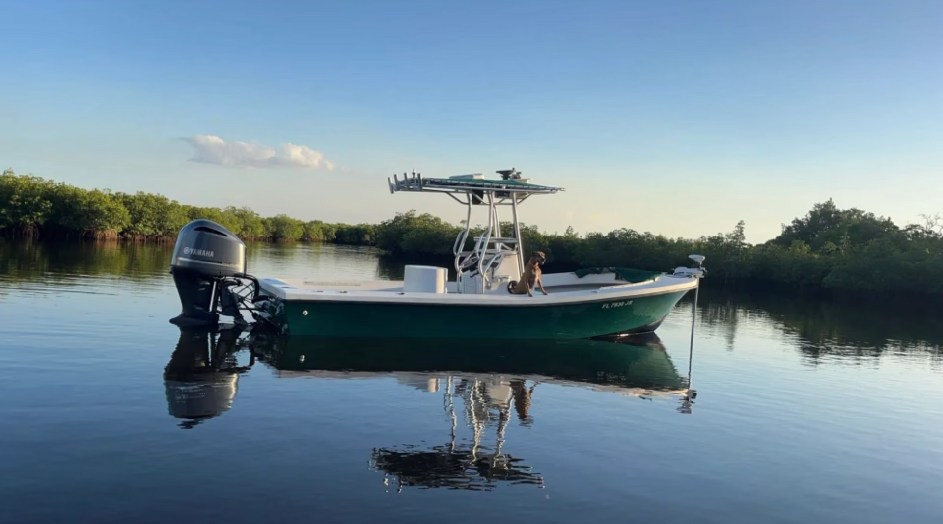 A green and white boat is floating on top of a body of water.