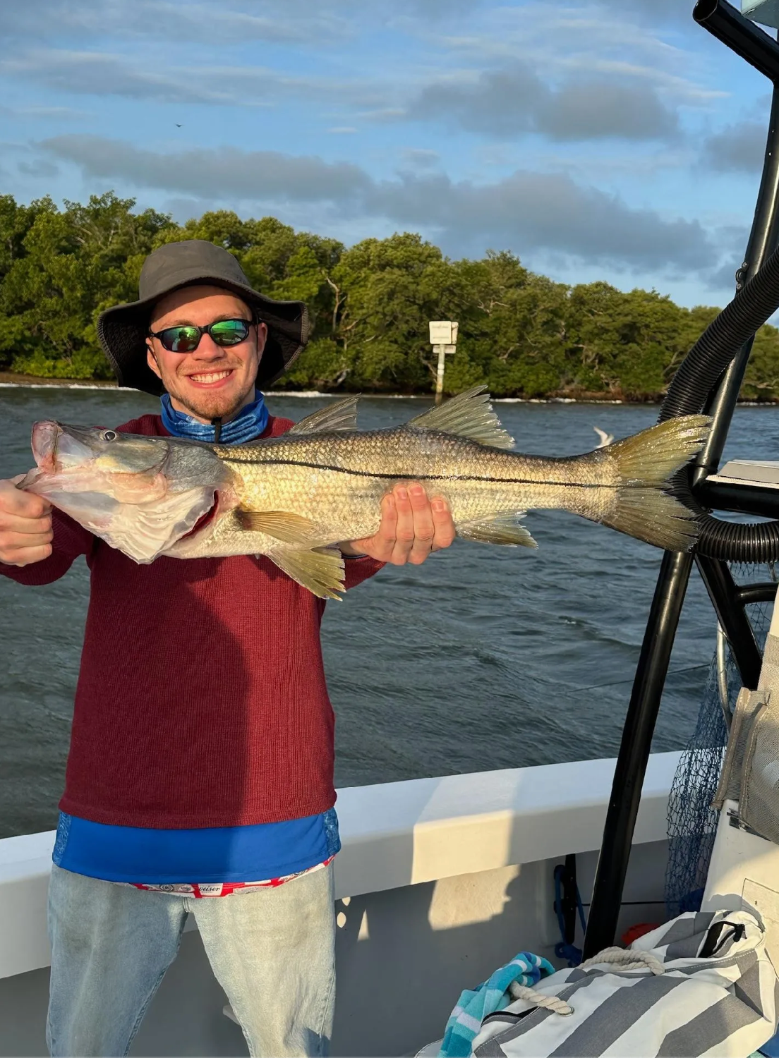 A man is holding a large fish on a boat.