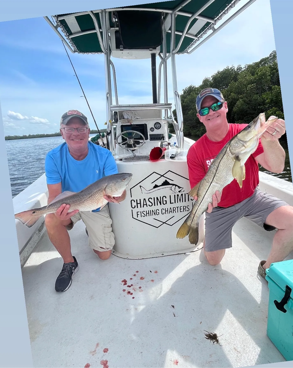 Two men are sitting on a boat holding fish.