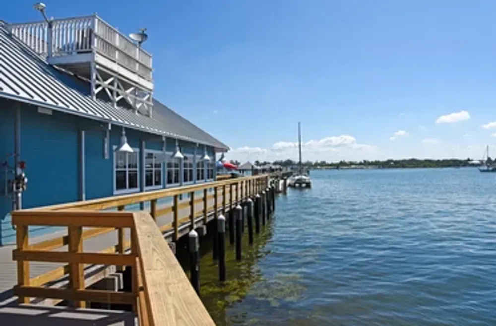 A blue building with a wooden deck overlooking a body of water.