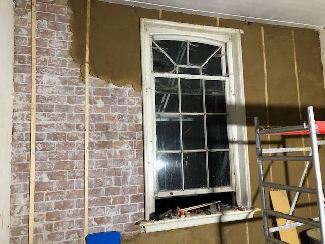 Leem op oud metselwerk. De latten zijn om te kunnen rijen. Zo wordt de laag overal even dik.