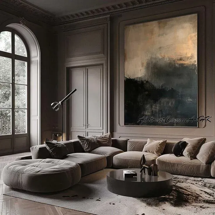 Cozy living room with large abstract painting, arched window, and a curved beige sofa.